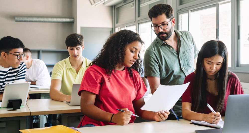 Students at desk with professor