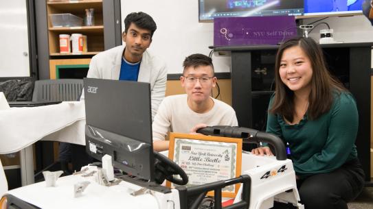 3 students gathered around self driving vehicle project