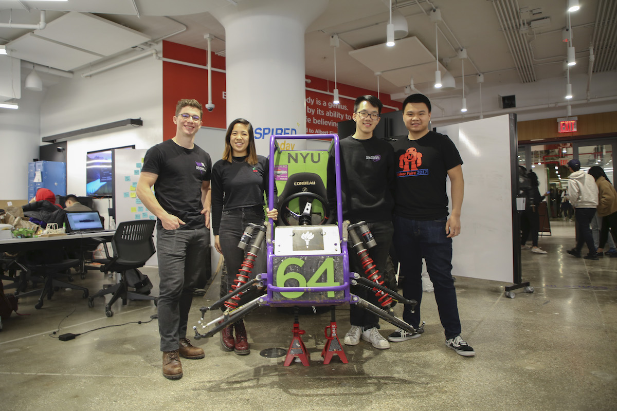 off-road vehicle flanked by students who built it